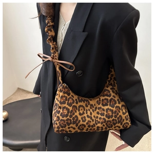 Detail of leopard print half-moon bag featuring pleated strap and leather bow knot detail