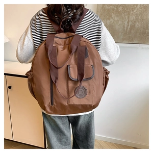 Detailed back view of a brown nylon travel backpack with adjustable straps on a model