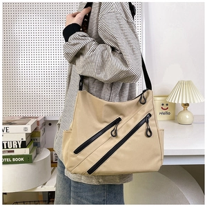 Vue détaillée du sac messager kaki avec poches zippées diagonales et texture en nylon