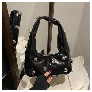 Détail du sac hobo en cuir noir brillant avec de grands clous argentés et fermeture éclair