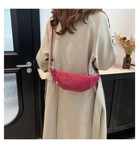 Detail view of magenta suede crescent bag with pleated structure and leather strap