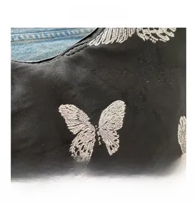 Close-up of butterfly embroidery and pleated texture on black fabric underarm bag