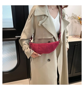 Detail of a dark red frosted crescent bag worn with a beige trench coat on a shoulder