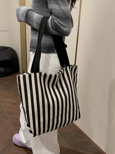 Lifestyle shot of large black and white striped canvas tote bag worn on shoulder