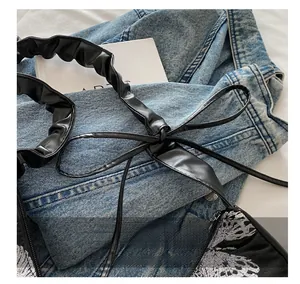 Close-up of black pleated PU shoulder strap with delicate butterfly embroidery details