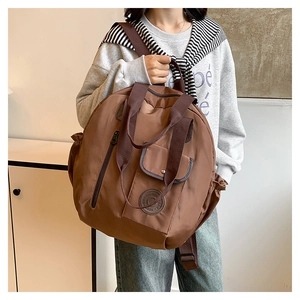 Detail view of large brown functional round backpack with multiple straps and pockets