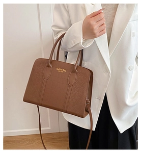 Detail of brown crocodile embossed tote bag with gold lettering and sturdy top handles