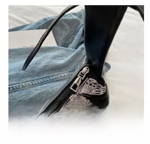 Close-up of smooth silver metal zipper on a black shoulder bag with butterfly embroidery