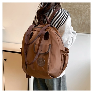 Close-up of a large dark brown backpack with side pockets and a stylish round logo