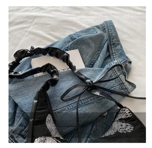 Detailed view of the butterfly embroidery and pleated handle on this black shoulder bag