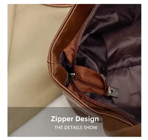 Detail of the smooth bronze zipper closure and brown leather texture on a tote bag