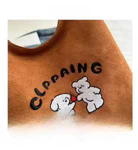 Detail of brown suede handbag featuring cute dog and bear embroidery with lettering