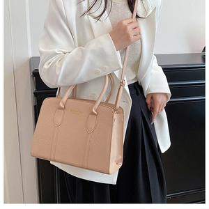 Detail of beige crocodile pattern tote bag with gold hardware and removable shoulder strap
