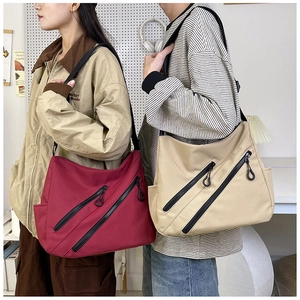 Détail de sacs bandoulière en toile bordeaux et kaki avec zip diagonal et large sangle