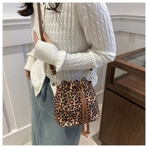 Detail view of leopard print drawstring bucket bag with adjustable brown shoulder strap