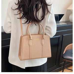 Detail of beige crocodile pattern tote bag featuring golden New York fashion branding