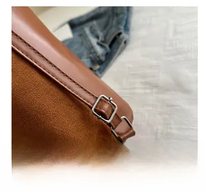 Close-up of brown leather and suede bucket bag with adjustable silver metal buckle detail