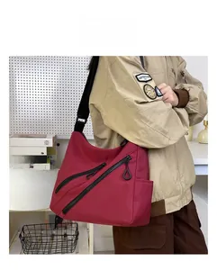Détail du sac messager en nylon bordeaux avec poches zippées et bandoulière ajustable