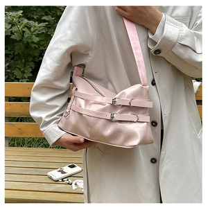 Pink faux leather shoulder bag featuring silver metal rings and decorative buckle straps