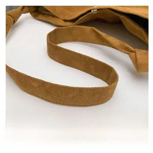 Detail shot of wide shoulder strap on brown suede tote bag showing soft texture