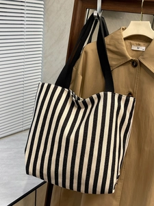Detail of striped canvas tote bag showing thick vertical stripes and wide black strap