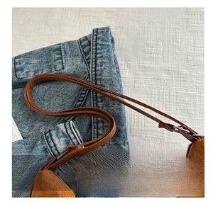 Detail of brown suede tote with leather strap styled on denim fabric surface