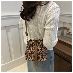Detailed view of leopard print bucket bag with drawstring and adjustable strap on a model