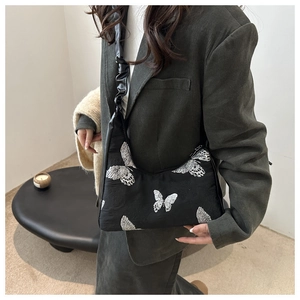 Detailed view of white butterfly embroidery and ruffled strap on black Hobo shoulder bag