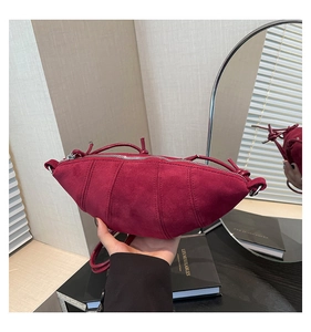 Detailed view of burgundy suede crescent bag with vertical stitching and silver zipper