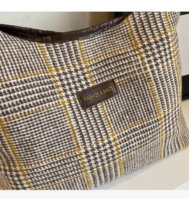Detail of classic houndstooth pattern bag with leather trim and gold fashion lettering