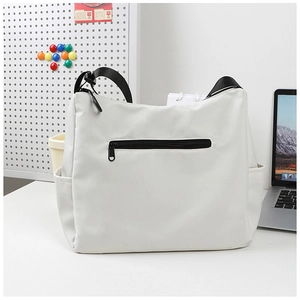 Détail du sac beige montrant la poche zippée arrière et la large bandoulière en nylon