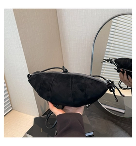 Minimalist black matte crescent crossbody bag with zipper and knotted strap detail