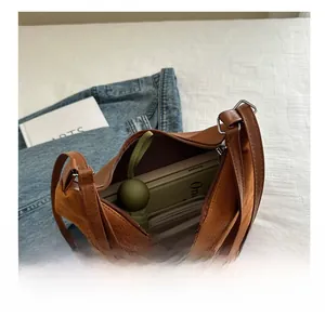 Macro view of brown leather bucket bag showing large interior capacity with a zipper