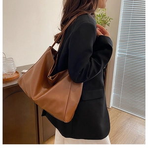 Brown soft PU leather tote bag shown on a model, highlighting the large capacity and texture