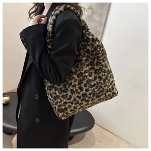 Détail d'un grand sac cabas en peluche léopard porté avec un blazer noir chic en hiver