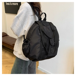 Detail view of large capacity black nylon backpack on shoulder in minimalist interior