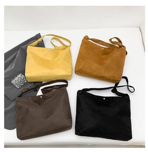 Detailed top view of four colors of matte suede tote bags with metal snap button closures