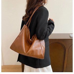 Model showing a large vintage brown tote bag over the shoulder in a minimalist room