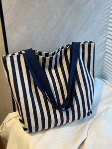Detailed side view of large canvas tote bag with navy blue and white vertical stripes