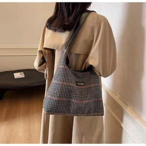 Close-up of houndstooth plaid tote bag with fashion label and leather trim detailing