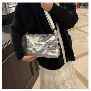 Detail showing metallic silver shoulder bag with decorative leather straps and metal buckles