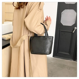 Detail shot of black wrinkled leather tote bag showing texture and minimalist design