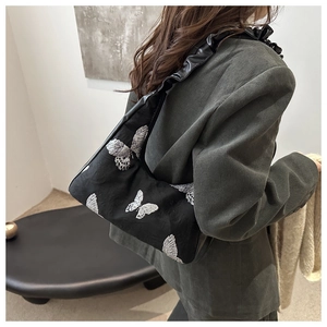 Detailed butterfly embroidery and pleated leather strap on a black shoulder bag