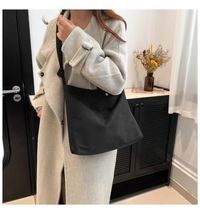 Detail of black matte tote bag on model showing large capacity and snap button closure