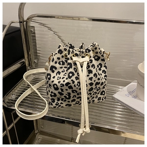 Detail of fashion leopard print bucket bag with canvas texture and white drawstring closure