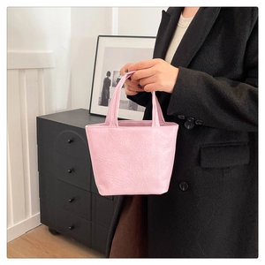 Detailed close-up of a pink pleated tote bag texture and handles in a minimalist setting