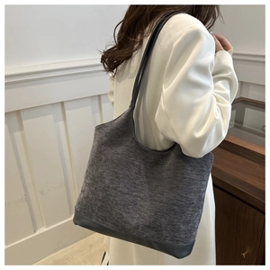 Deep grey textured fabric tote bag with leather base and slim black straps shown on model