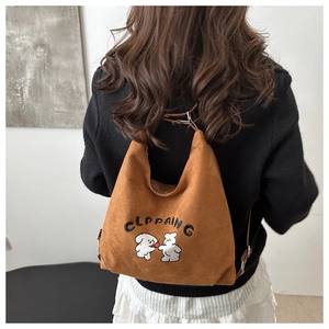 Detail of a brown suede shoulder bag featuring cute animal embroidery and adjustable strap