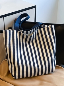 Close-up of blue and white striped canvas tote bag with durable navy webbing handles