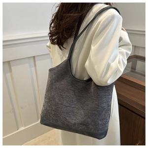 Detail view of a large grey tote bag worn on shoulder by a model for a commute look